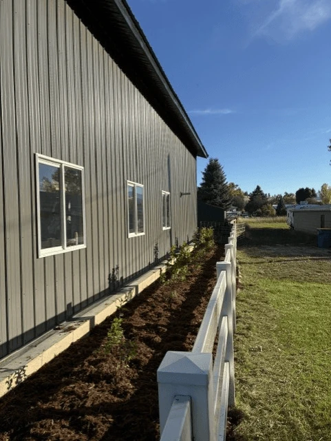 Cedar bed along a building behind a white fence